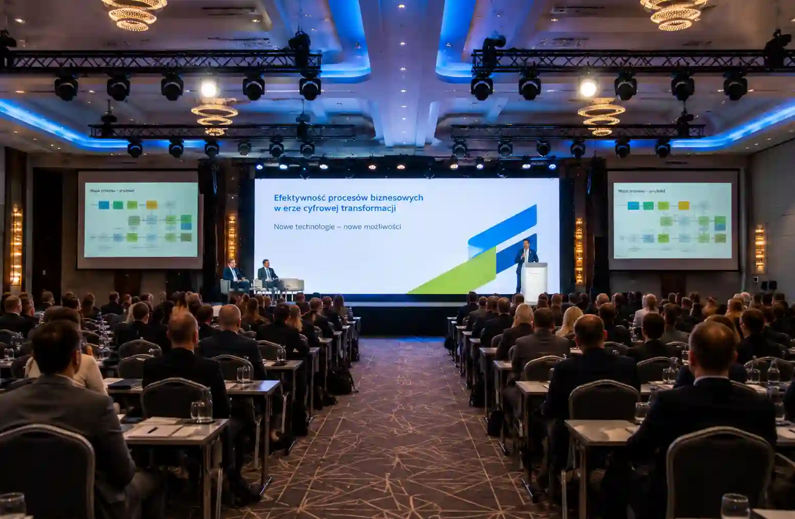 Nowoczesna sala konferencyjna podczas Forum MotoSolutions w Krakowie. Prelegent występuje przed publicznością, prezentując rozwiązania dla branży automotive.
